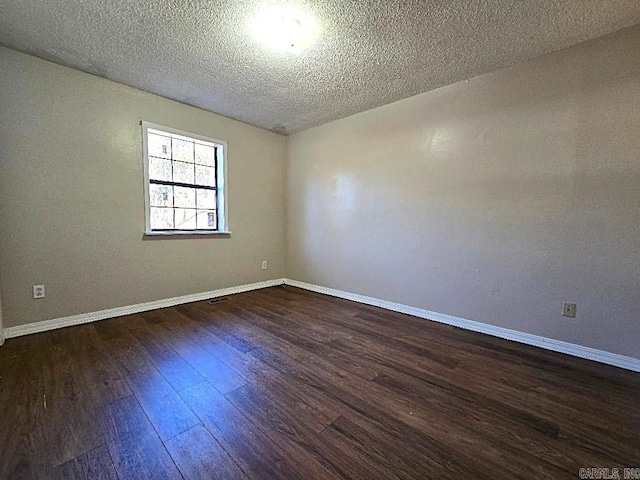 spare room with dark wood-type flooring and a textured ceiling