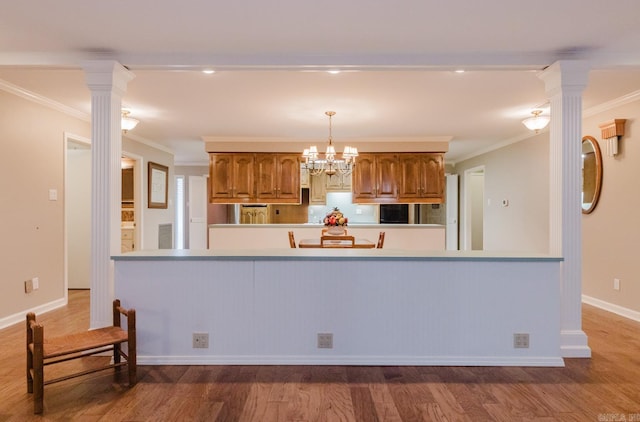 kitchen featuring ornamental molding, hanging light fixtures, ornate columns, and wood-type flooring