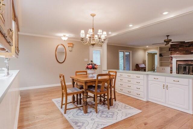 dining room featuring ceiling fan, ornamental molding, light wood-type flooring, and a fireplace