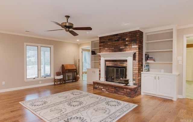 living room with a fireplace, light hardwood / wood-style flooring, crown molding, and ceiling fan