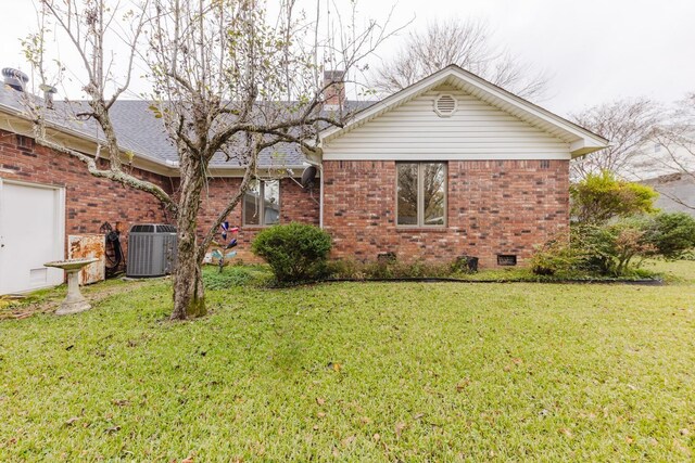 rear view of property with central air condition unit and a lawn