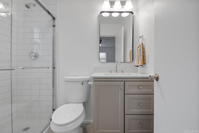 bathroom featuring ceiling fan, toilet, a shower with door, and vanity