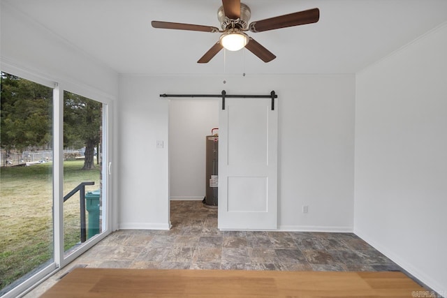 spare room with a barn door, ceiling fan, and water heater