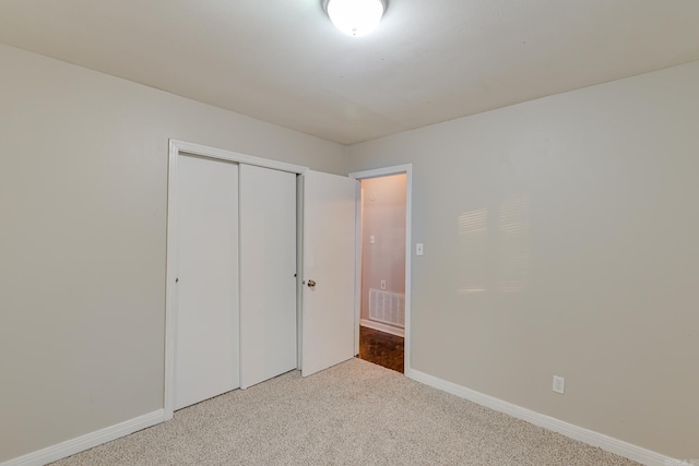 unfurnished bedroom featuring light carpet and a closet