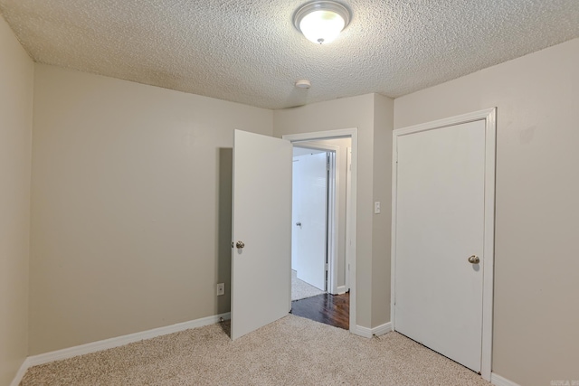 unfurnished bedroom featuring light carpet, a textured ceiling, and a closet