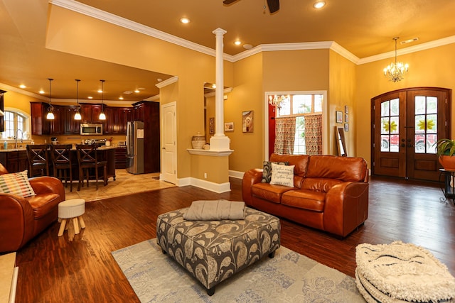 living room with sink, crown molding, decorative columns, wood-type flooring, and french doors