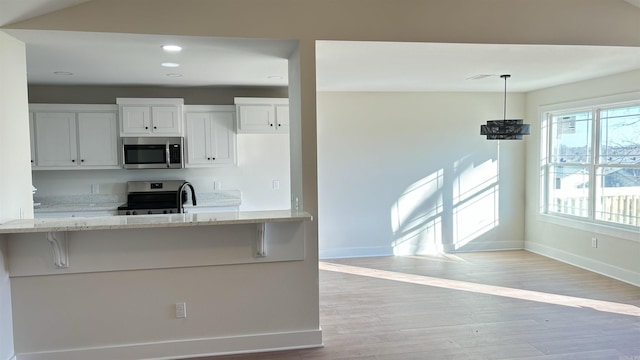 kitchen with white cabinets, a breakfast bar, stainless steel appliances, and hanging light fixtures