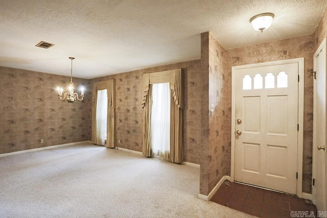 carpeted entryway with a textured ceiling and an inviting chandelier