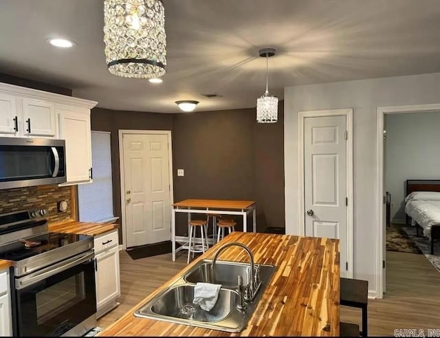 kitchen with white cabinets, sink, appliances with stainless steel finishes, and wood counters