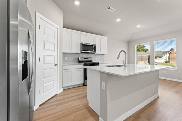 kitchen with a kitchen island with sink, white cabinets, sink, appliances with stainless steel finishes, and light hardwood / wood-style floors