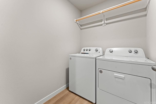 clothes washing area with separate washer and dryer and light hardwood / wood-style flooring