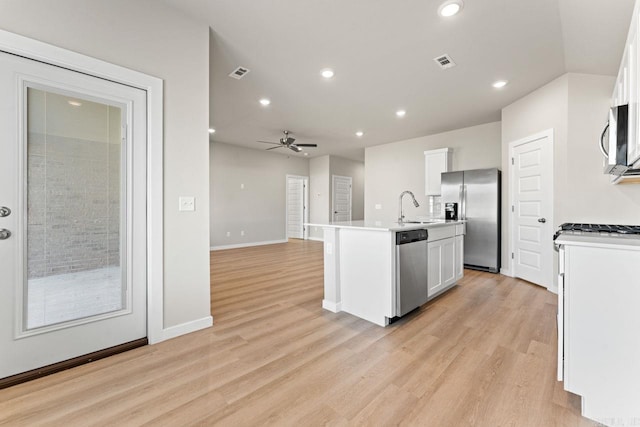 kitchen with a kitchen island with sink, sink, light hardwood / wood-style flooring, appliances with stainless steel finishes, and white cabinetry