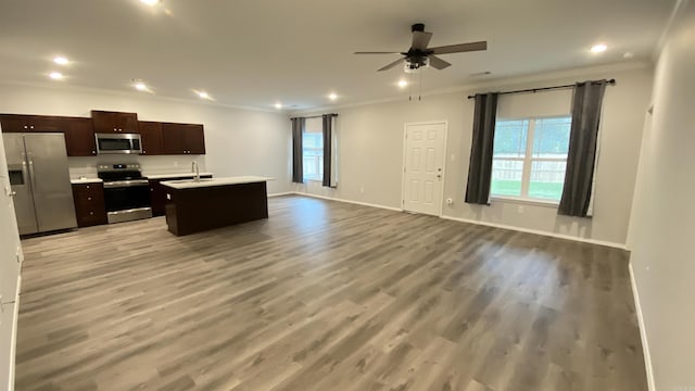 kitchen featuring appliances with stainless steel finishes, light wood-type flooring, ceiling fan, sink, and a center island with sink