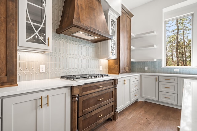 kitchen with stainless steel gas cooktop, dark hardwood / wood-style floors, custom range hood, a healthy amount of sunlight, and white cabinets