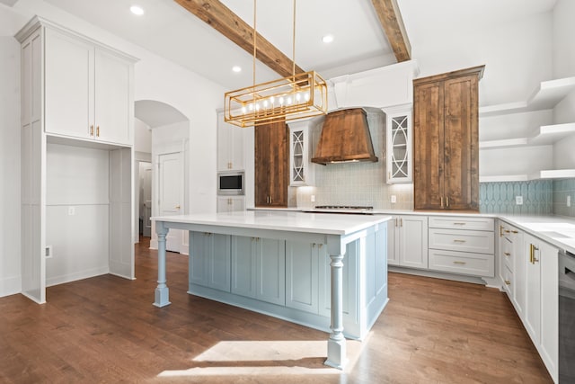 kitchen with a kitchen bar, decorative light fixtures, a kitchen island, beam ceiling, and white cabinets