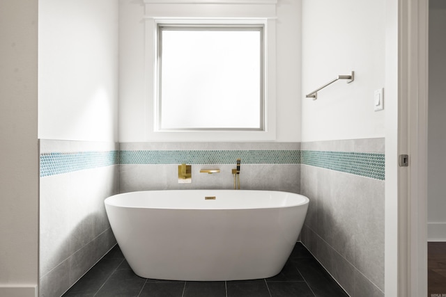 bathroom with a tub, tile walls, and tile patterned floors