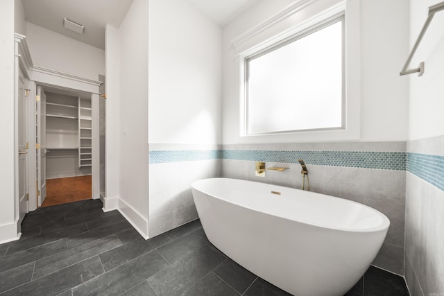 bathroom with tile patterned flooring, tile walls, and a tub