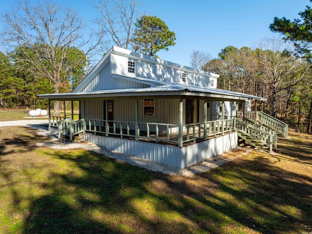 rear view of property featuring covered porch and a yard