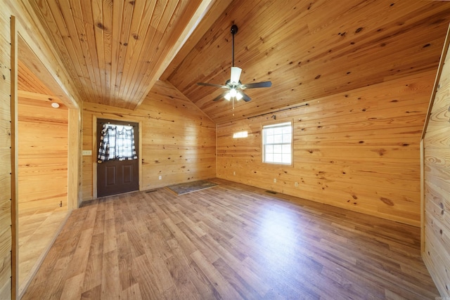 spare room featuring vaulted ceiling with beams, wooden walls, light hardwood / wood-style floors, and wooden ceiling