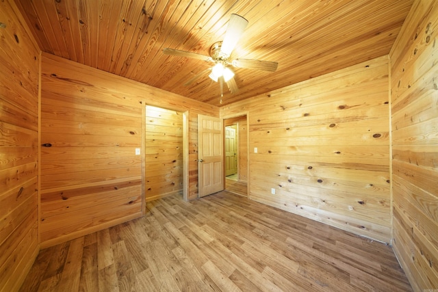 spare room with ceiling fan, hardwood / wood-style flooring, wood ceiling, and wood walls