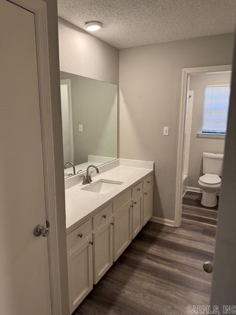 full bathroom featuring shower / bath combination with curtain, a textured ceiling, vanity, hardwood / wood-style flooring, and toilet