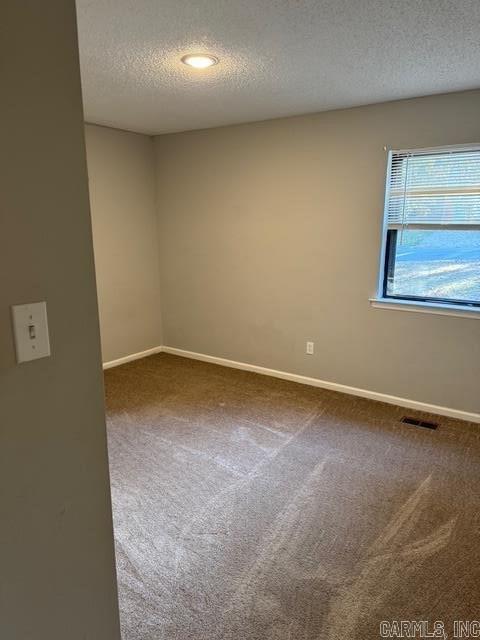 carpeted empty room featuring a textured ceiling