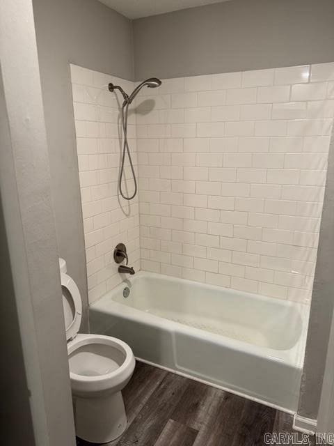 bathroom with hardwood / wood-style flooring, toilet, and tiled shower / bath