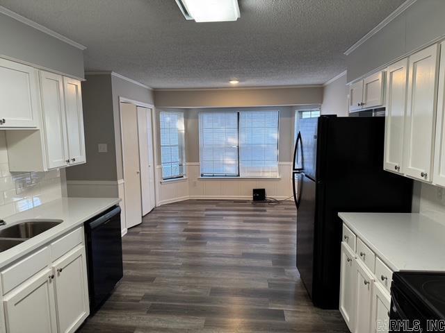 kitchen with white cabinets, dark hardwood / wood-style floors, black dishwasher, and a wealth of natural light