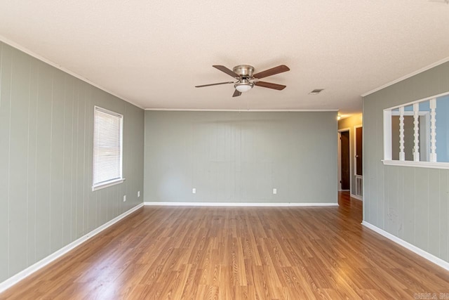 spare room featuring wooden walls, hardwood / wood-style flooring, ceiling fan, and ornamental molding