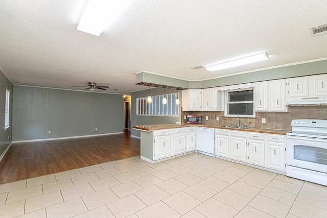 kitchen featuring kitchen peninsula, tasteful backsplash, white appliances, sink, and white cabinets