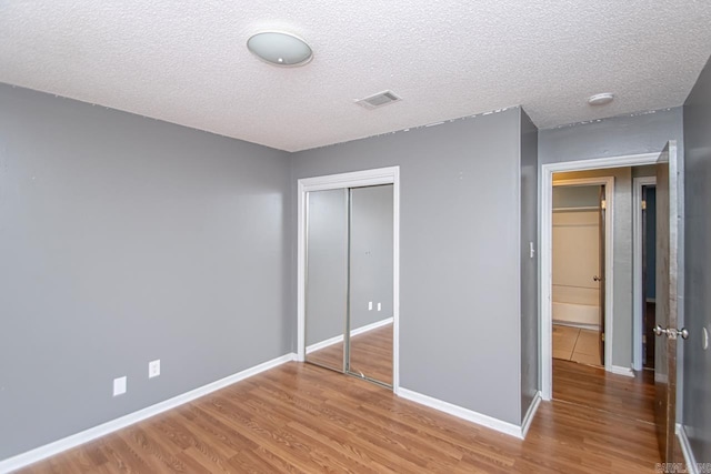 unfurnished bedroom featuring a textured ceiling, hardwood / wood-style flooring, and a closet