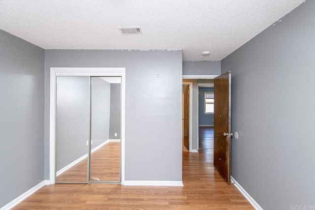 unfurnished bedroom featuring a closet, light hardwood / wood-style floors, and a textured ceiling