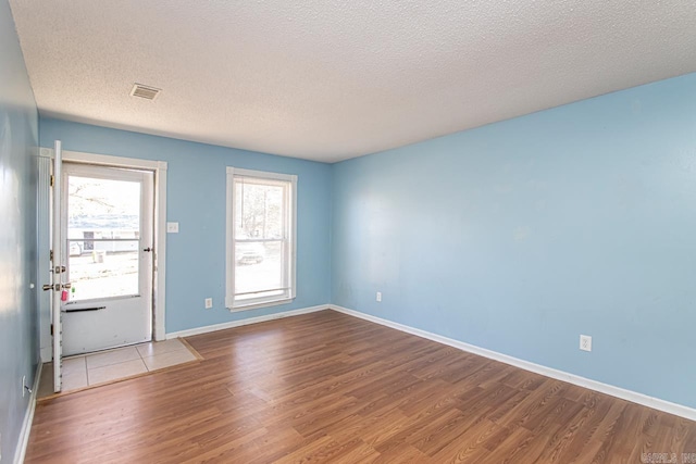 empty room with light hardwood / wood-style flooring and a textured ceiling