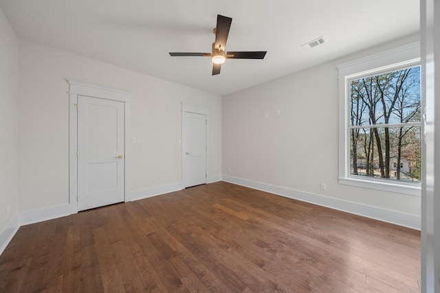 unfurnished bedroom with multiple windows, dark hardwood / wood-style flooring, and ceiling fan