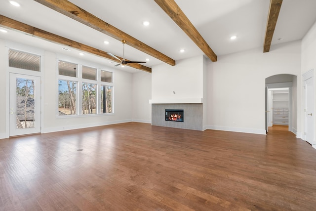 unfurnished living room with beam ceiling, ceiling fan, dark hardwood / wood-style flooring, and a fireplace