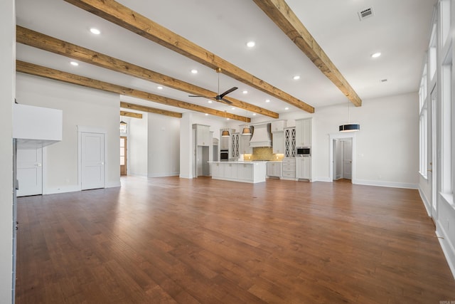 unfurnished living room featuring dark hardwood / wood-style flooring, beam ceiling, and ceiling fan