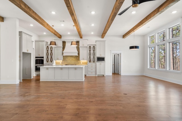 unfurnished living room featuring beam ceiling, dark wood-type flooring, and ceiling fan