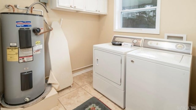 washroom with cabinets, light tile patterned floors, electric water heater, and washing machine and clothes dryer