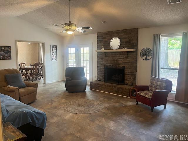 living room featuring a fireplace, a textured ceiling, vaulted ceiling, and ceiling fan