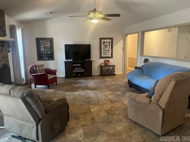 living room featuring ceiling fan, lofted ceiling, and a fireplace