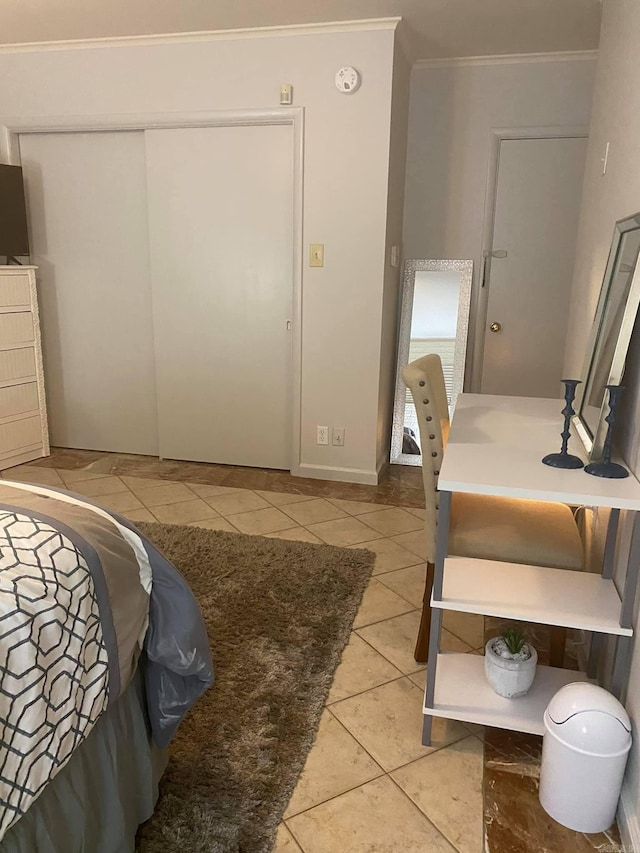 bedroom with light tile patterned floors, a closet, and crown molding