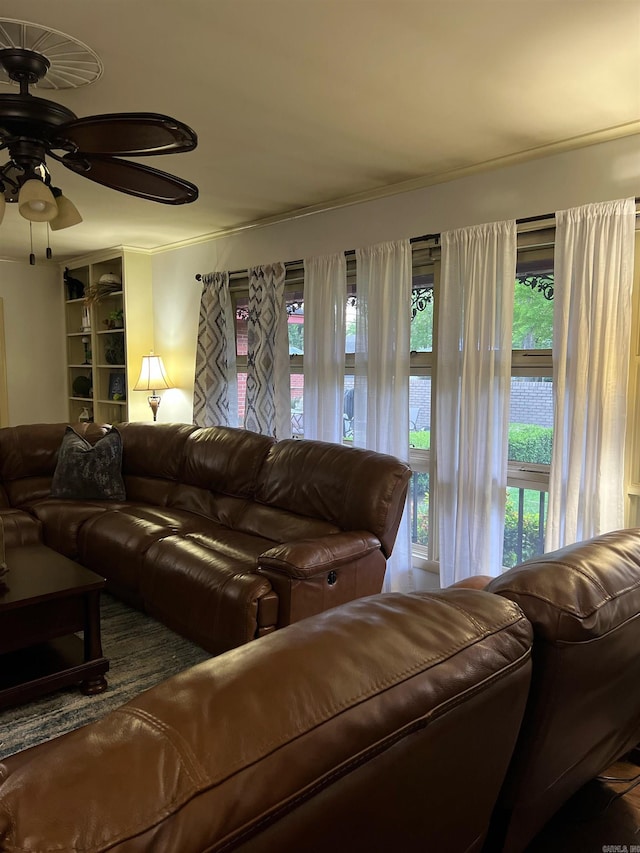 living room featuring ceiling fan, crown molding, and a healthy amount of sunlight