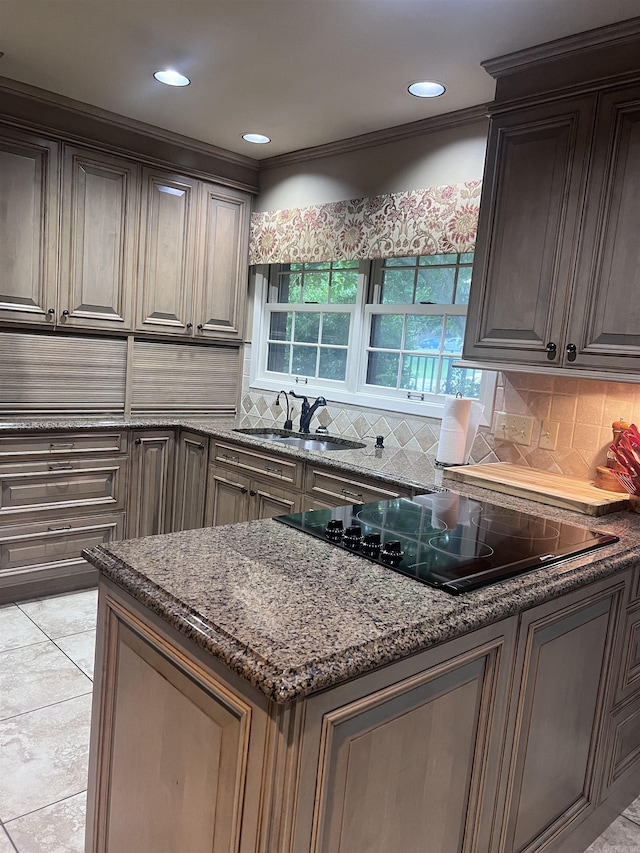 kitchen with dark stone counters, black electric stovetop, sink, ornamental molding, and tasteful backsplash