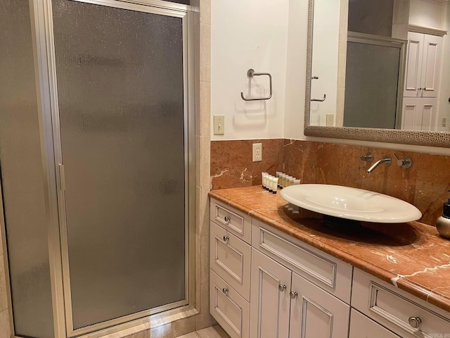 bathroom with vanity, an enclosed shower, and tile walls