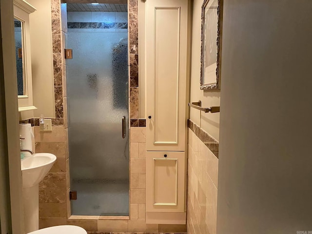 bathroom featuring toilet, tile walls, and a shower with shower door