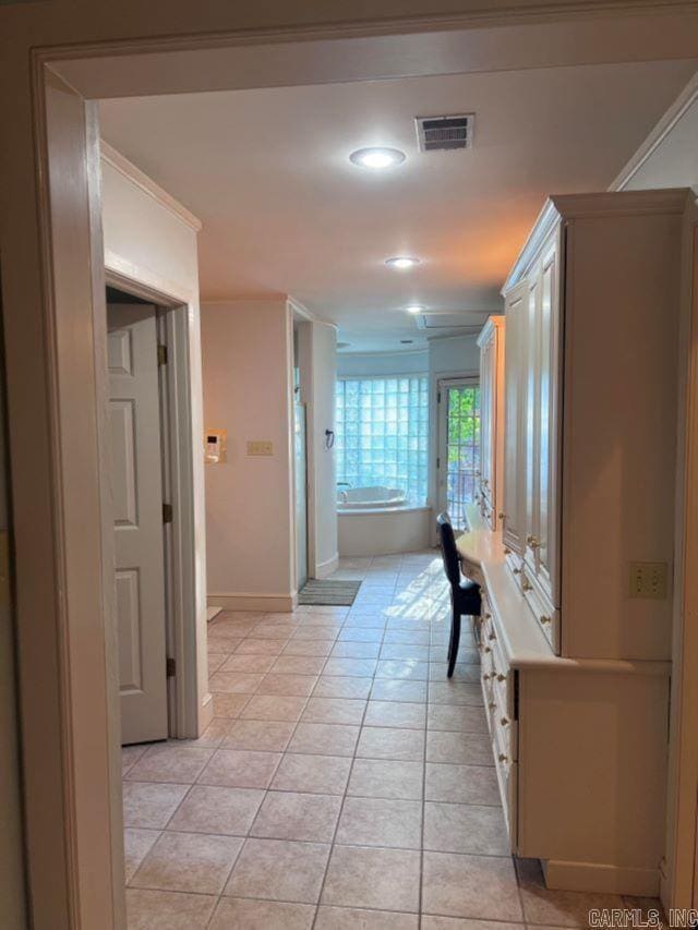 corridor with light tile patterned floors and ornamental molding