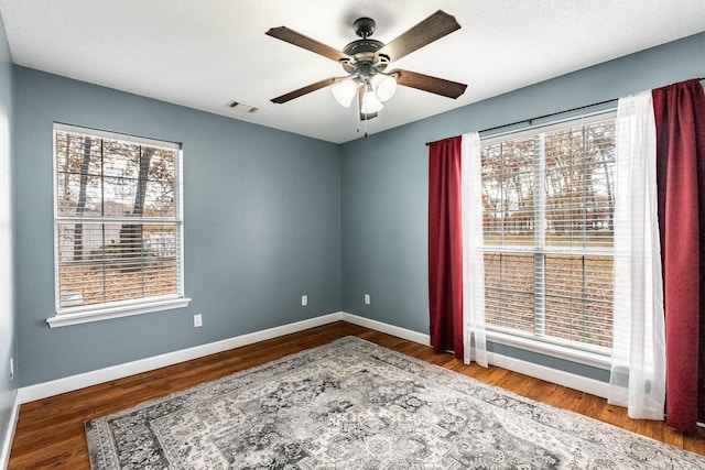 spare room with hardwood / wood-style floors, ceiling fan, and a healthy amount of sunlight