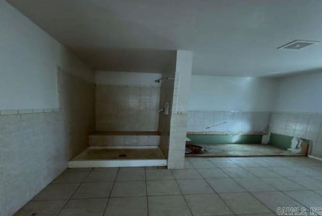 bathroom featuring tile patterned floors, tiled shower, and tile walls