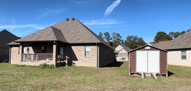 rear view of house featuring a porch, an outbuilding, a lawn, and a shed