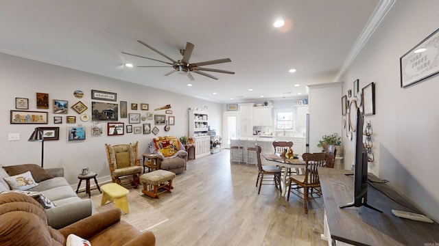 living room with crown molding, ceiling fan, and light wood-type flooring